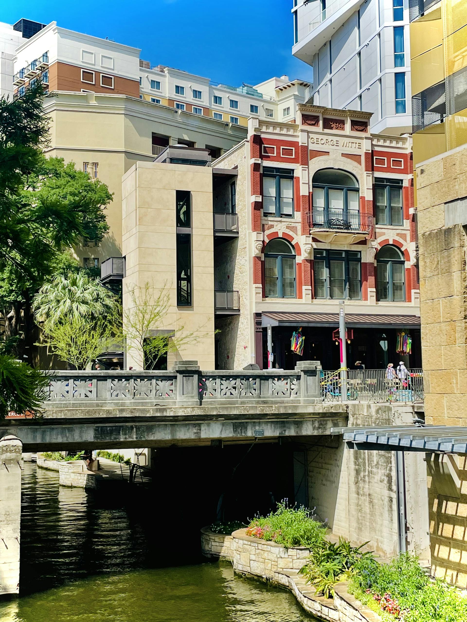 Scenic view of San Antonio's Riverwalk with historic architecture and lush greenery.