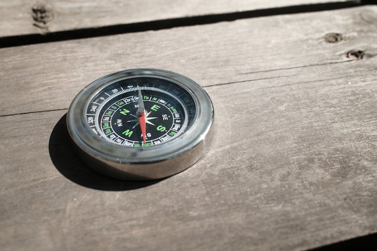 Close-up of a vintage compass on a rustic wooden surface, illustrating exploration and navigation themes.